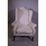 A Georgian style wing armchair with high back, raised on cabriole supports