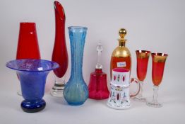 A ruby glass decanter with gilded decoration, a glass bell and various coloured glass vases,