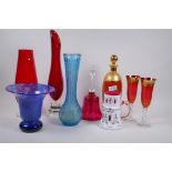 A ruby glass decanter with gilded decoration, a glass bell and various coloured glass vases,