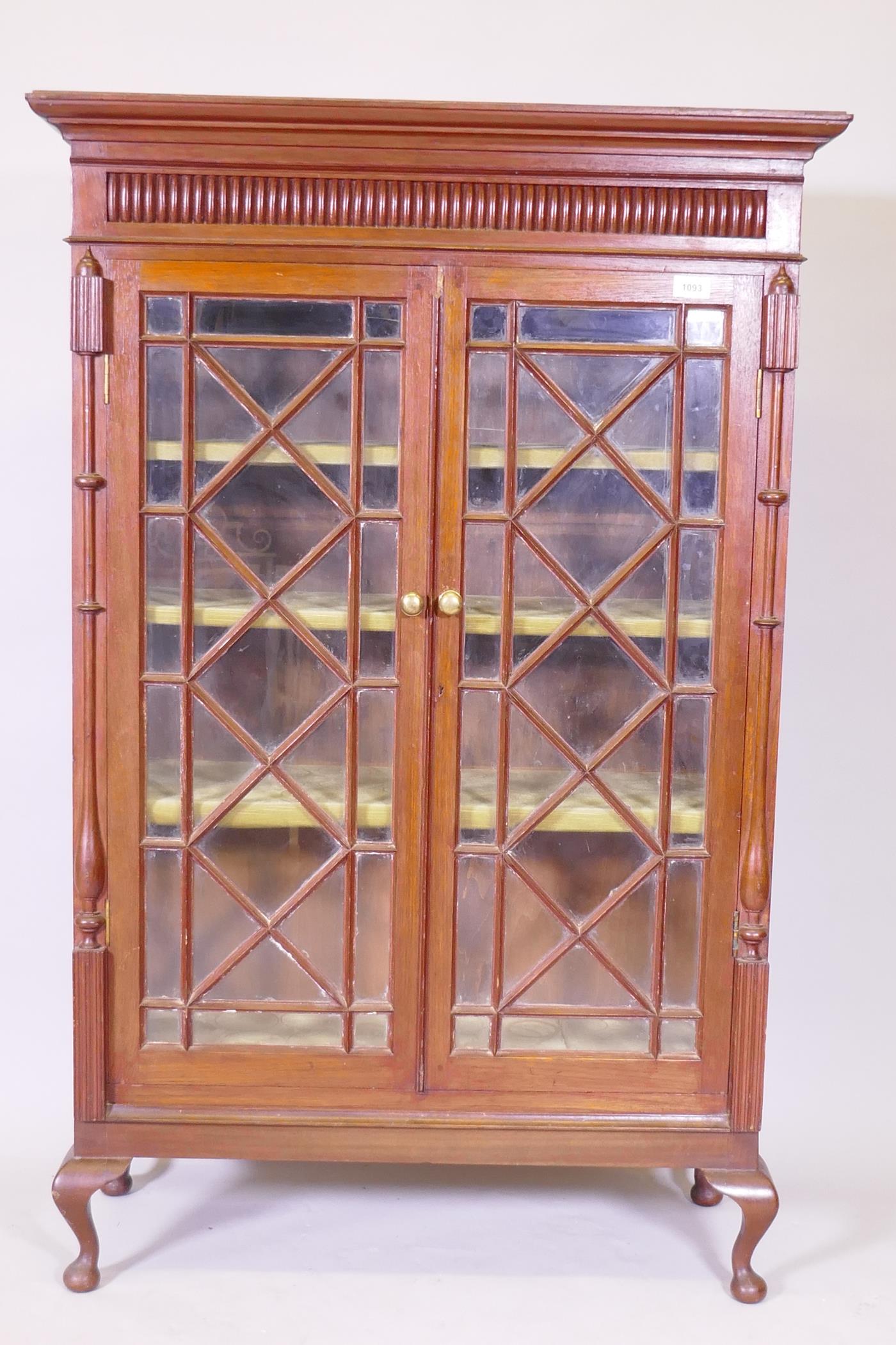 A late C19th Anglo Indian teak glazed cabinet, with carved frieze over two doors flanked by columns,