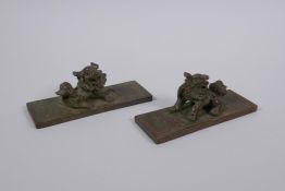 A pair of Chinese bronze scroll weights with kylin mounts, character marks to base, 11cm long