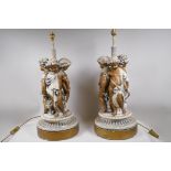 A pair of painted and parcel gilt table lamps in the form of three putti, 64cm high