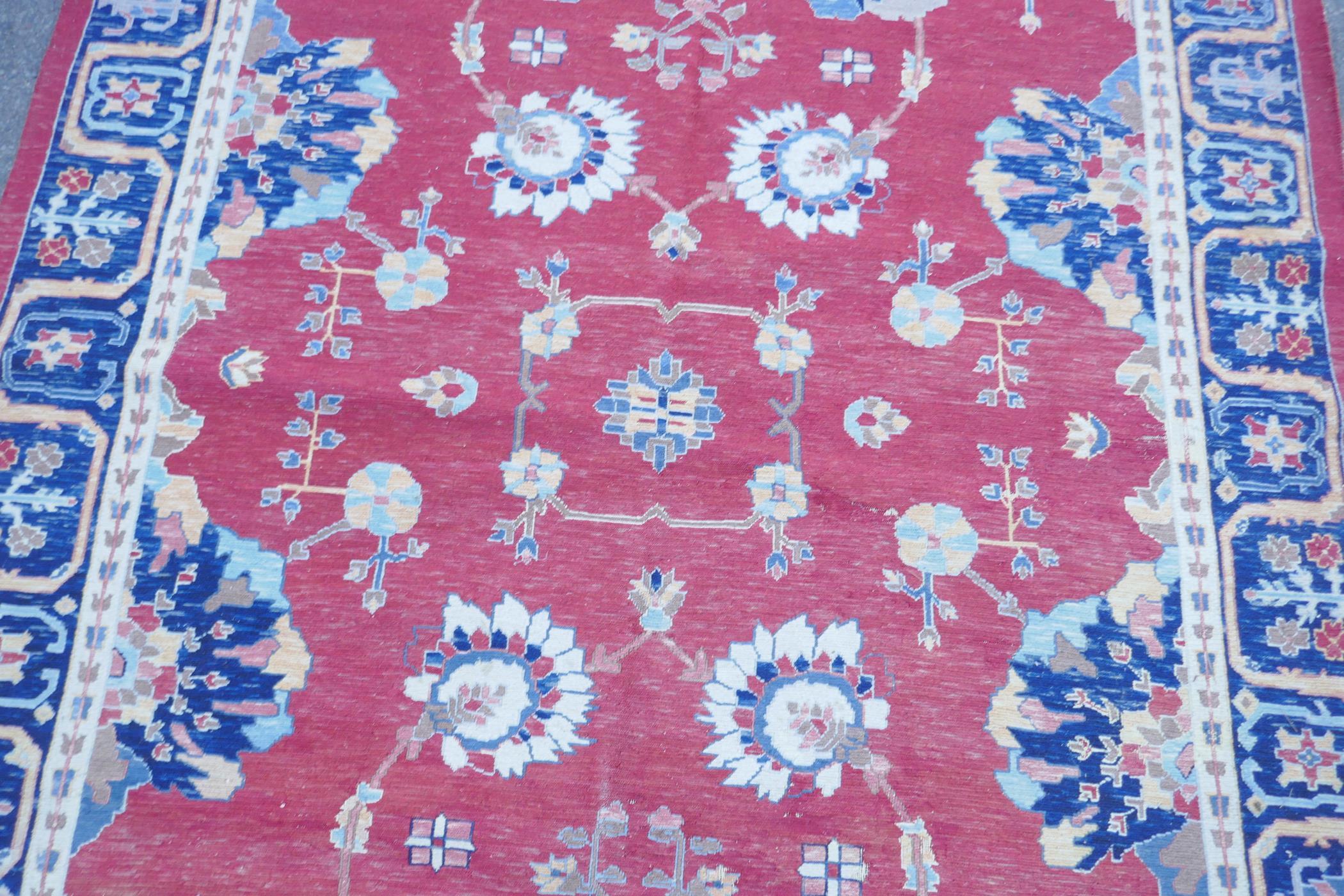 A Middle Eastern hand woven wool carpet with stylised floral designs on a faded red field, 320 x - Image 3 of 9