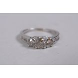 A 10ct white gold diamond ring, with three central stones and stone set shoulders, size N