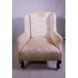 An antique wing armchair with shaped back, raised on cabriole supports with claw and ball feet and
