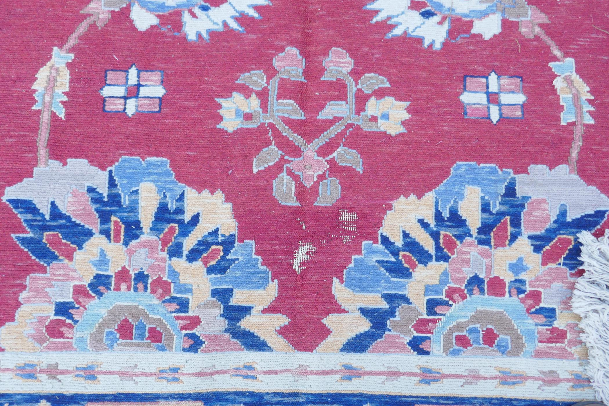 A Middle Eastern hand woven wool carpet with stylised floral designs on a faded red field, 320 x - Image 7 of 9