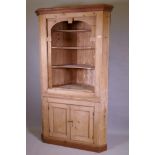 A C19th stripped pine standing corner cupboard with shaped open shelves above two cupboards,