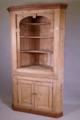 A C19th stripped pine standing corner cupboard with shaped open shelves above two cupboards,