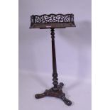 A rosewood book trough mounted on a stand, with carved turned column and platform base with scroll