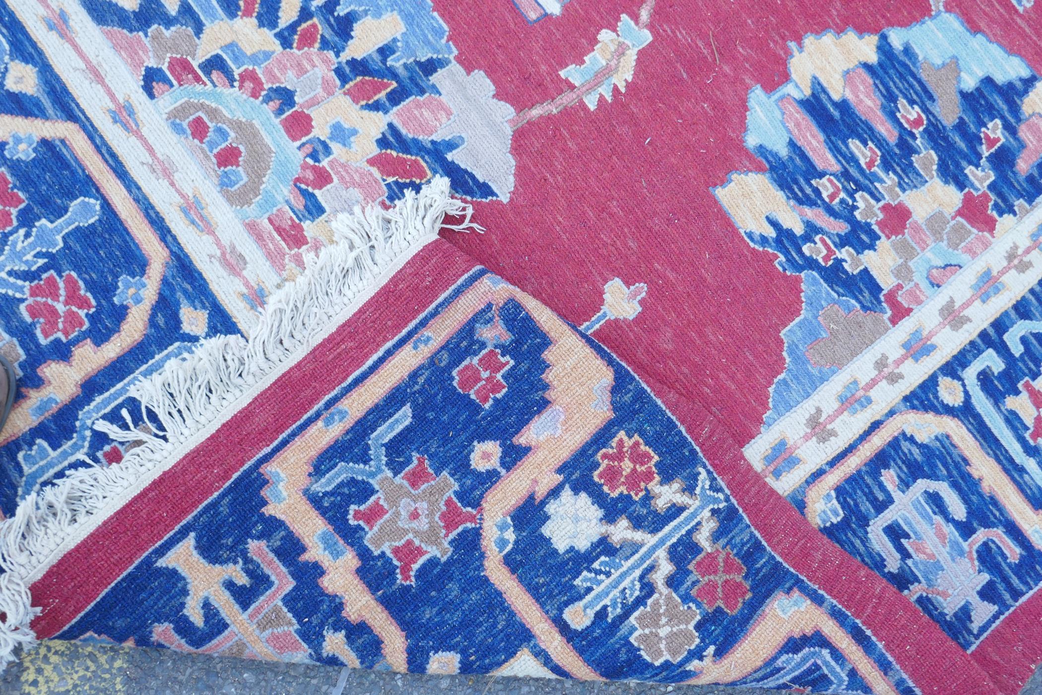 A Middle Eastern hand woven wool carpet with stylised floral designs on a faded red field, 320 x - Image 6 of 9