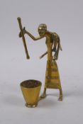An African Benin style brass figure of a mother carrying a child and using a pestle and mortar, 13cm