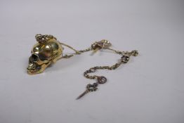 A brass Albert style skull and bone watch chain, 33cm long