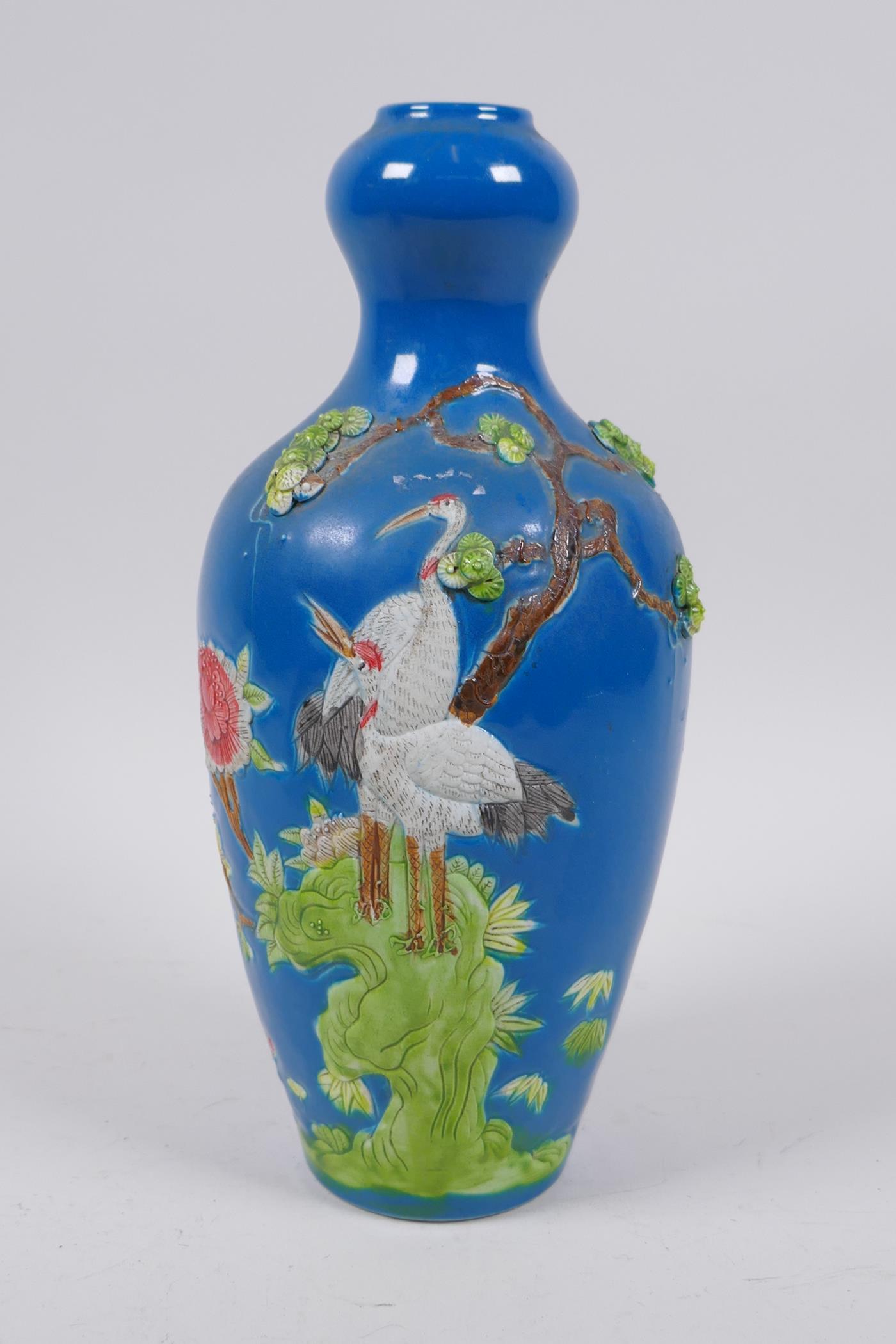 A Chinese blue ground porcelain garlic head shaped vase with raised and painted red crowned crane