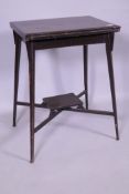 An Edwardian mahogany card table with fold over top, raised on splay supports united by an