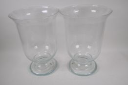 A pair of blown glass hurricane vases on pedestal feet, 39cm high, 27cm diameter