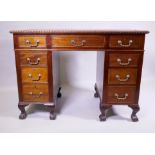 A mahogany nine drawer pedestal desk with inset leather top and gadrooned edge, raised on cabriole