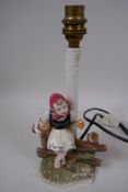 An Austrian Belvedere pottery table lamp modelled as a young girl sitting on a fence, 28cm high