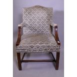 A Georgian style hump back mahogany framed open arm chair, raised on moulded supports united by an H