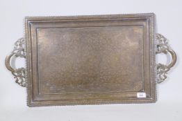 A Kashmiri brass tray with pierced handles and finely engraved decoration of scrolling foliate