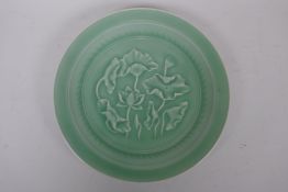 A Chinese celadon plate with raised decoration of water lilies, impressed seal mark to base, 26cm