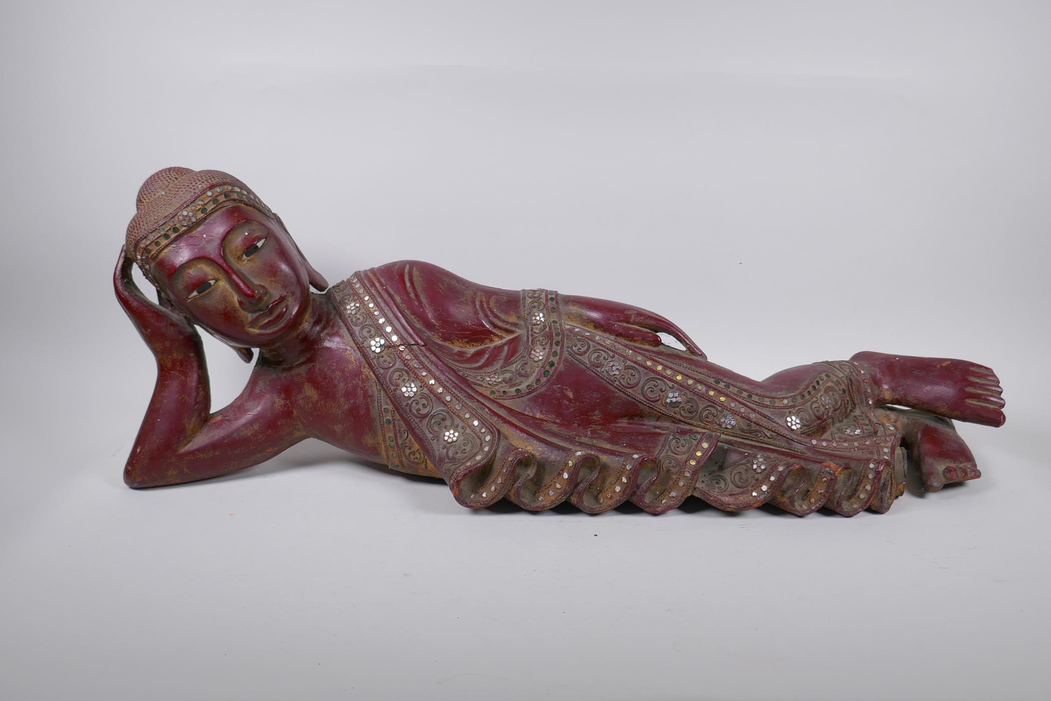 An antique Burmese carved and lacquered wood reclining figure of Buddha, 78cm long