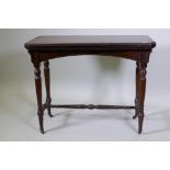 A Victorian mahogany card table, with fold out top, raised on turned supports united by a stretcher,