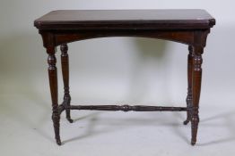 A Victorian mahogany card table, with fold out top, raised on turned supports united by a stretcher,
