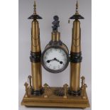An architectural bronze mantel clock raised on two tall spires and plinth base, the clock with