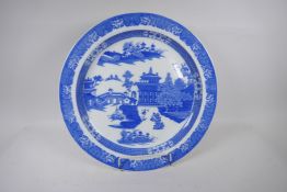 A large Staffordshire blue and white charger decorated with a variation of the Willow pattern,