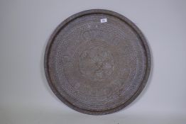 An antique Middle Eastern brass tray engraved with Islamic calligraphy and geometric designs, 68cm