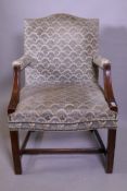 A Georgian style hump back mahogany framed open arm chair, raised on moulded supports united by an H