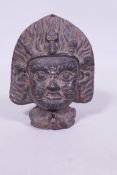 An antique Eastern/Tibetan black glazed terracotta votive Buddhistic mask, with flaming halo and