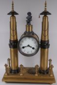 An architectural bronze mantel clock raised on two tall spires and plinth base, the clock with
