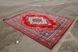 A Belgian deep red ground wool carpet with an oriental floral medallion design, 250cm x 342cm