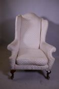 A Georgian style wing armchair with high back, raised on cabriole supports