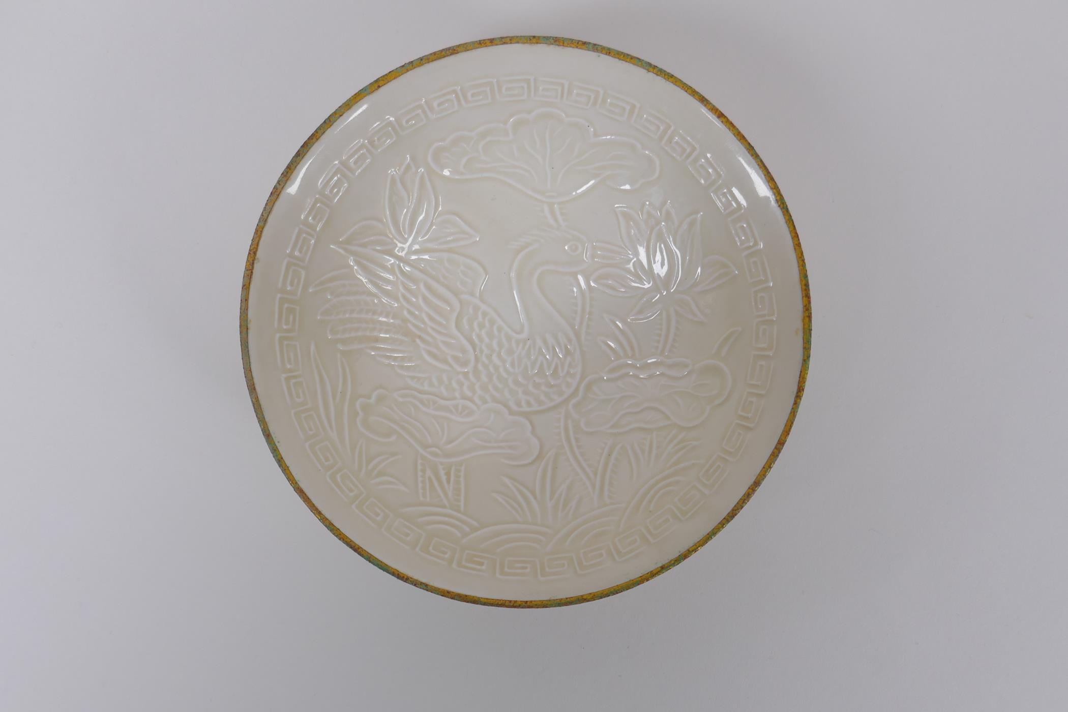 A Chinese Dingware porcelain dish with raised waterfowl decoration and a gilt metal rim, marks to