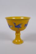 A Chinese imperial style yellow ground porcelain stem cup with blue and white stork decoration,