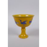 A Chinese imperial style yellow ground porcelain stem cup with blue and white stork decoration,