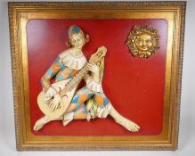 A Spanish 3D wood and composition wall plaque depicting a musician in harlequin clothing, 90 x 80cm