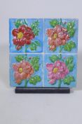 A set of four Majolica tiles with raised floral motifs mounted on a wood stand, 32 x 34cm