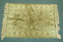 A wool silk mix rug with central design on a moss green field, 140 x 100cm