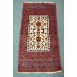 A Middle Eastern hand woven rug with red borders and central panel, with geometric floral designs