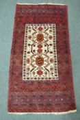 A Middle Eastern hand woven rug with red borders and central panel, with geometric floral designs