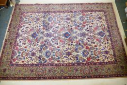 An Indo Persian wool carpet with multi-colour all over floral design on an ivory field, signed to