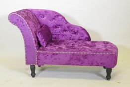 A contemporary chaise longue of small proportions, raised on turned supports