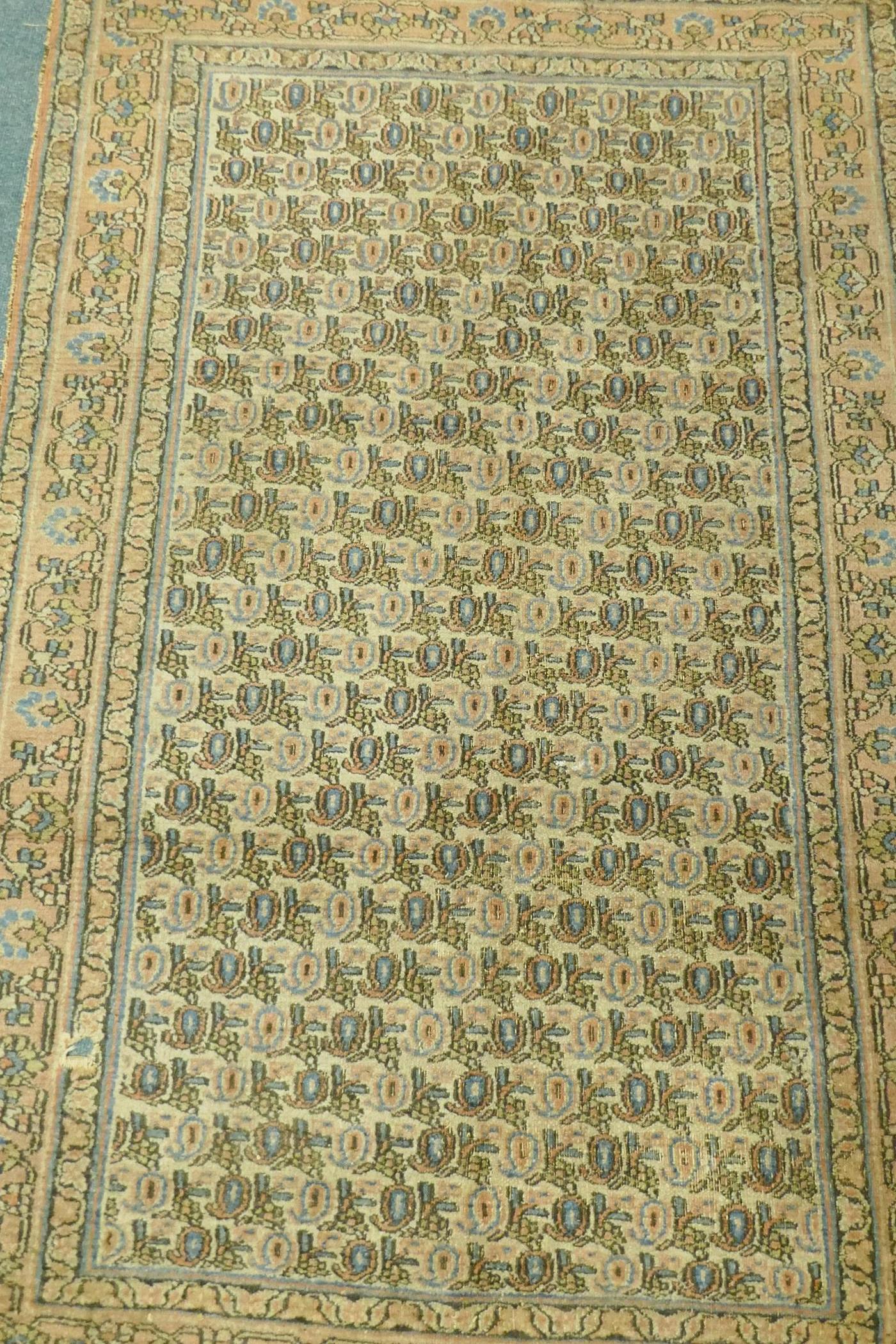 A Middle Eastern hand woven wool carpet with all over geometric designs on a faded terracotta field, - Image 2 of 4