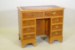 An eight drawer yew wood kneehole desk with tooled leather inset top, 91 x 50cm, 77cm high