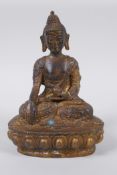 A Tibetan bronze of Buddha seated on a lotus throne, with the remnants of gilt patina