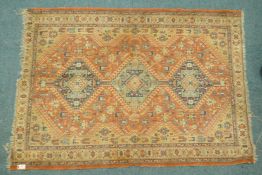 A Middle Eastern wool carpet with medallion design on a faded terracotta field, 160 x 110cm