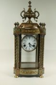 A brass mantel clock with urn finial and twisted columns, painted enamel dial and spring driven